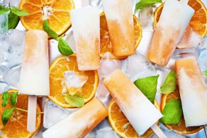 Orange cream popsicles with orange slices, basil, and ice
